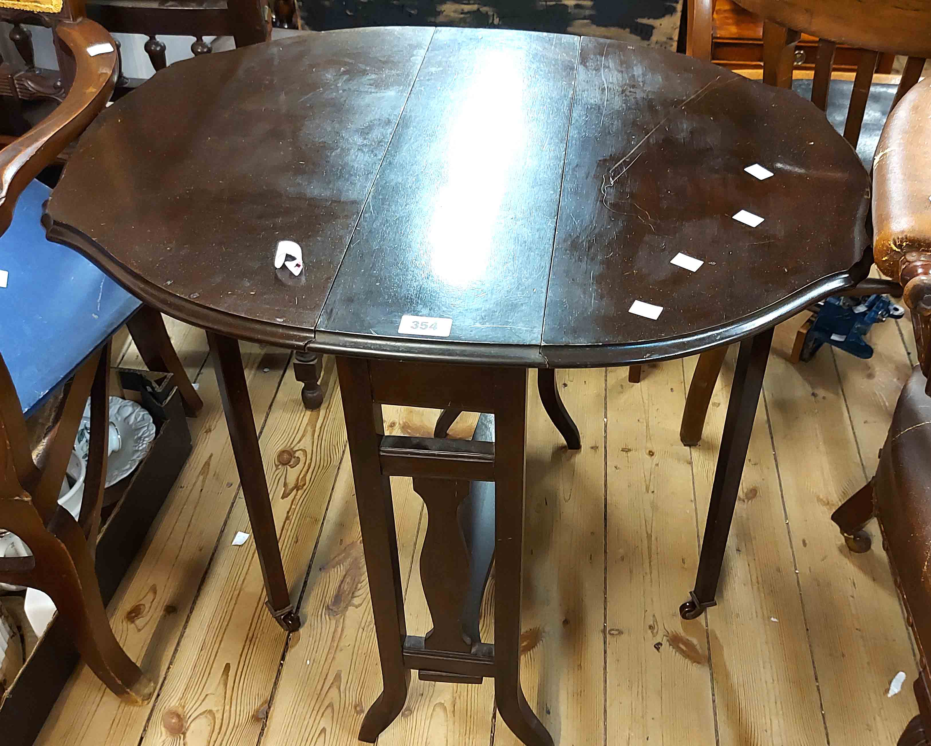 A 60cm Edwardian stained mahogany Sutherland table with shaped top, set on pierced standard ends