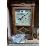 A vintage oak cased mantel clock with visible pendulum and eight day gong striking movement