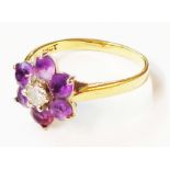 A marked 18ct yellow metal ring, set with central small diamond within a six stone amethyst border -