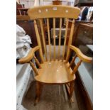 A 20th Century blonde wood high lathe back rocking chair with solid sectional seat, set on turned