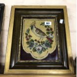A 19th Century shield shaped embroidered panel depicting a bird with a floral border, set in later