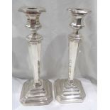 A pair of 25cm high silver candlesticks with tapered faceted stems and loaded stepped bases -