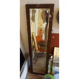 An old oak framed narrow bevelled oblong wall mirror