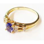 A 375 (9ct.) gold ring, set with central oval tanzanite flanked by tiny diamonds - size Q 1/2
