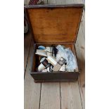 An antique lift-top wooden box containing a quantity of sewing related items including cotton reels,