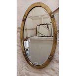 An 80cm early 20th Century brass clad framed bevelled oval wall mirror with applied boss