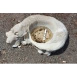 A cast concrete bird bath in the form of the reclining dog