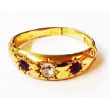 An 18ct. gold gypsy set ring with central diamond flanked by two small rubies - size O