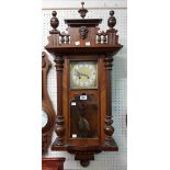 A late 19th Century walnut cased Vienna style wall clock with Arabic numerals, visible pendulum