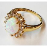 A 585 (14ct.) gold ring, set with central oval cabochon opal within a cubic zirconia white stone