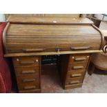 A 1.2m vintage oak roll-top desk with part-fitted interior and eight flanking pedestal drawers