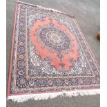A modern machine made Persian pattern rug with large central motif within a wide border on salmon