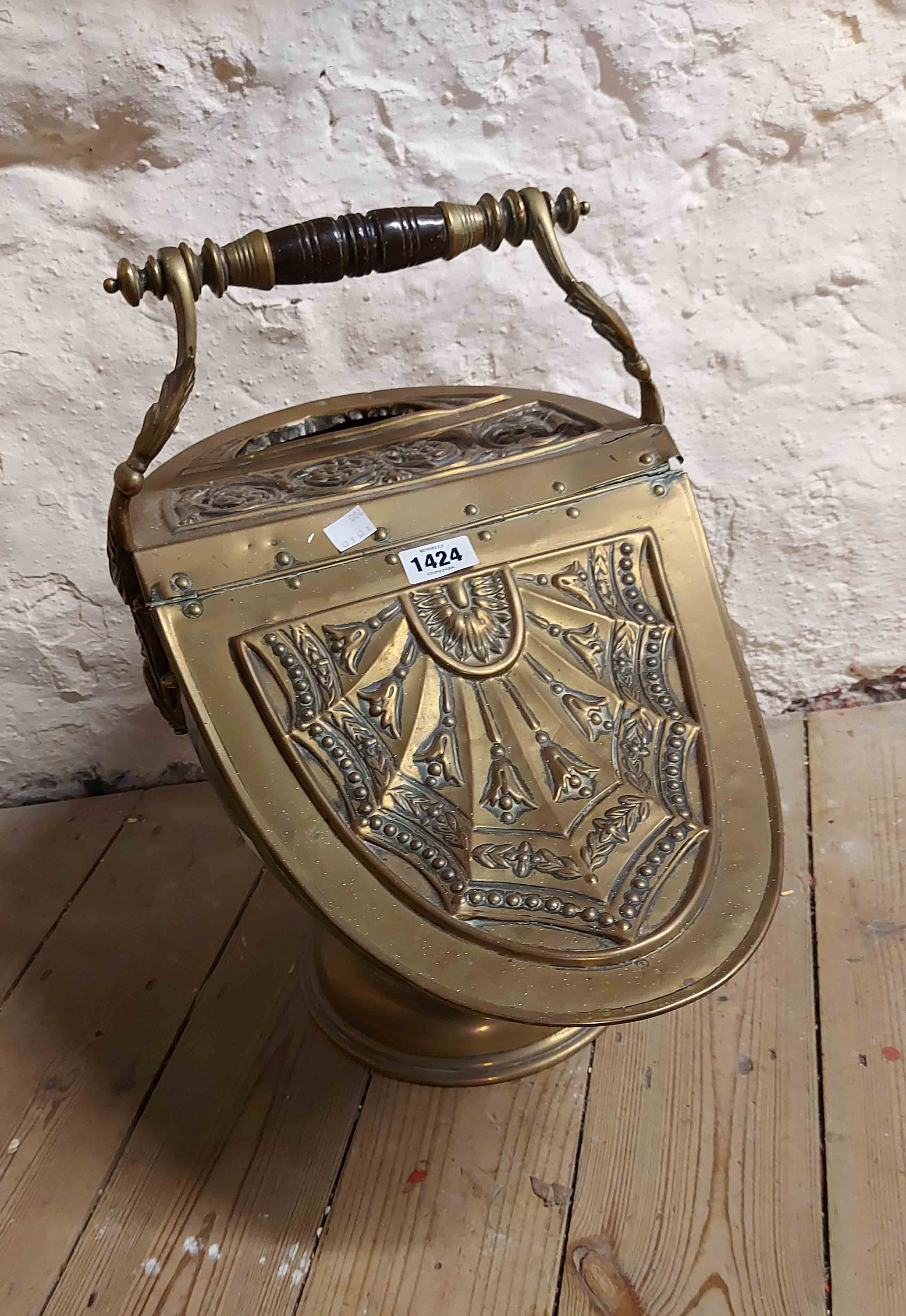 A 19th Century brass coal scuttle of lift-top helmet form with embossed floral decoration,