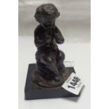 A small spelter figure depicting a child playing the pipes with antique finish, set on ebonised wood