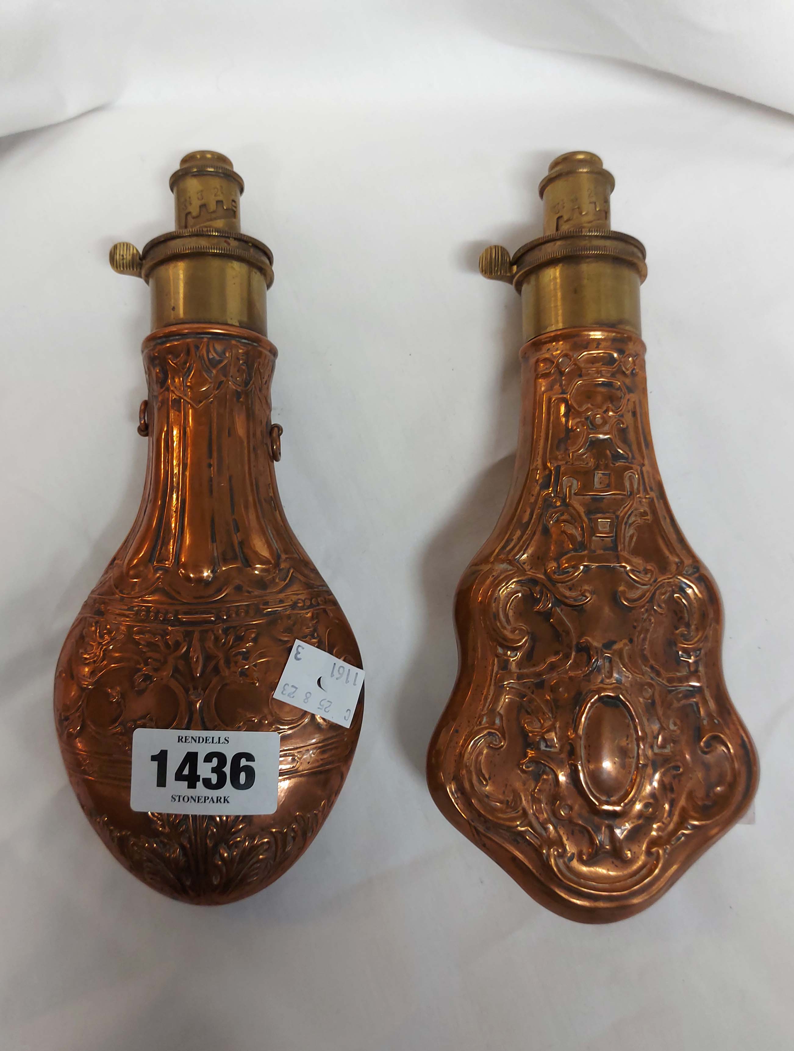 Two brass mounted copper powder flasks, each with embossed Rococo scrolling decoration