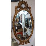 A 1.08m high ornate giltwood style resin framed bevelled oval wall mirror in the antique style