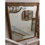 A gilt framed bevelled oblong wall mirror with decorative border