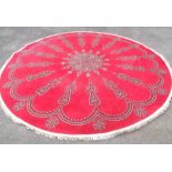 A large circular vintage machine made rug with radial motifs on bright red ground - 3.3m diameter