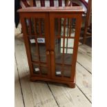 A miniature glass fronted mixed wood display cabinet with internal drawers