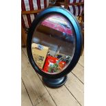 A modern oval mirror on pedestal stand with ebonised finish