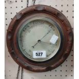 A late Victorian carved stained oak framed circular wall barometer with printed dial and aneroid