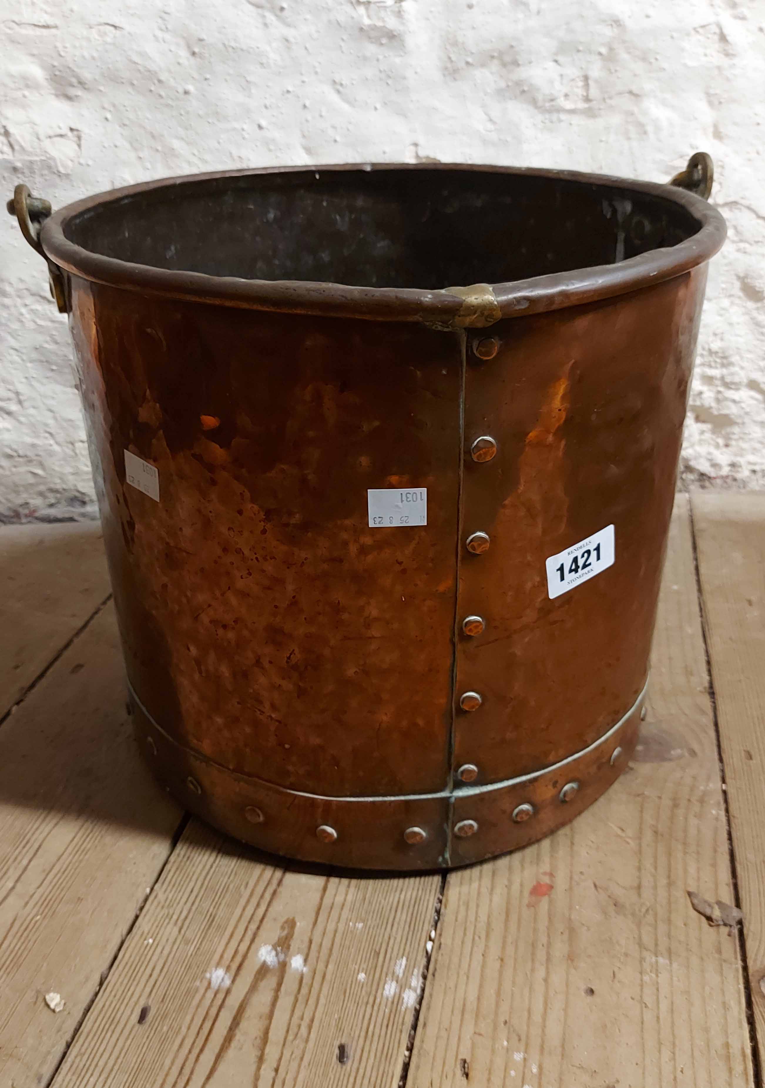 A large old copper log basket of riveted construction with brass handle