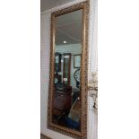 A modern gilt framed bevelled narrow oblong wall mirror with decorative pierced border