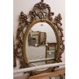 A reproduction ornate Rococo style gilt resin framed oval wall mirror