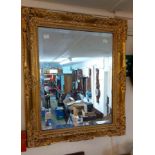 A gilt framed bevelled oblong wall mirror with decorative border