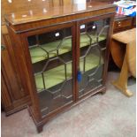 An 84cm early 20th Century stained walnut book cabinet with material lined shelves enclosed by a