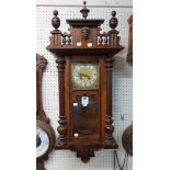 A late 19th Century walnut cased Vienna style wall clock with Arabic numerals, visible pendulum