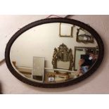 A 1920's stained walnut framed bevelled oval wall mirror with beaded border