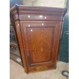 A 90cm antique oak wall hanging corner cupboard enclosed by a decorative inlaid panel door with