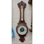 A late Victorian ornate carved wood framed banjo barometer/ thermometer with visible aneroid works