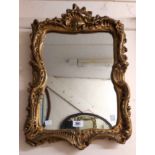 A vintage gilt plaster framed ornate Rococo style wall mirror with shaped border
