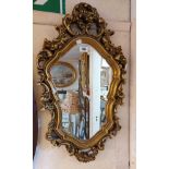 A vintage ornate gilt plaster framed Rococo style wall mirror with pierced foliate scroll border