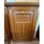 A 1.1m early 20th Century oak corner cupboard with shelves enclosed by a panelled door