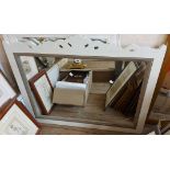 A white painted framed bevelled oblong wall mirror with pierced floral pediment - sold with a