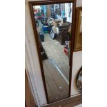 A modern stained wood framed narrow oblong wall mirror
