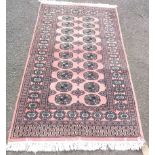 A modern handmade wool Bokara rug with two rows of gul motifs within a double border on pink