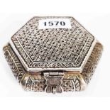An Indian ornate white metal hexagonal box with latch to the hinged lid