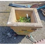 A concrete planter of tapered square form, set on wrought iron scroll feet - sold with a