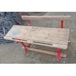 A Vintage school desk of bench form, with wooden top and bench, set on a cast-iron base