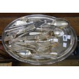An oval tea tray containing a quantity of assorted silver plated cutlery