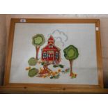 A vintage framed embroidered panel, depicting a building amidst trees