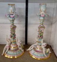 A pair of German porcelain candlesticks with putti and encrusted floral decoration