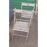 A pair of teak framed folding chairs with slatted backs and seats