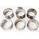 A set of six silver napkin rings with engine turned decoration and engraved initials to cartouche
