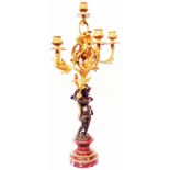 A large bronze and ormolu five branch figural candelabrum, depicting a putto holding a Rococo scroll