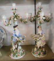 A pair of 19th Century German porcelain table candelabra each decorated with a figure holding a